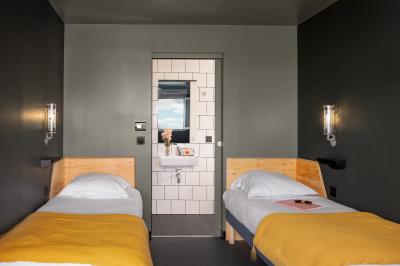 Chambre moderne avec lits superposés en bois, table ronde, chaise, et porte donnant sur l'extérieur.