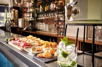 Distributeur de boisson citronnée sur pied, avec plateau de charcuterie et verre garni de menthe au premier plan.
