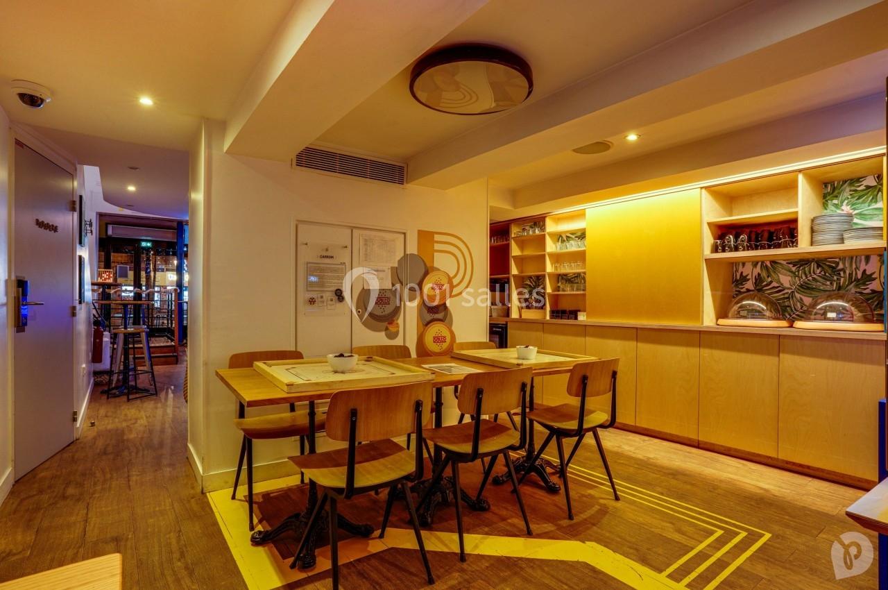 Salle à manger lumineuse avec table en bois, chaises assorties et étagères remplies de vaisselle et décorations.