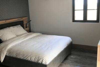 Lit avec tête de lit en métal blanc, draps et oreillers blancs, lampe de chevet sur une table contre un mur vert.