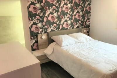 Lit avec tête de lit en métal blanc, draps et oreillers blancs, lampe de chevet sur une table contre un mur vert.