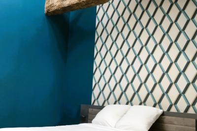 Lit avec tête de lit en métal blanc, draps et oreillers blancs, lampe de chevet sur une table contre un mur vert.