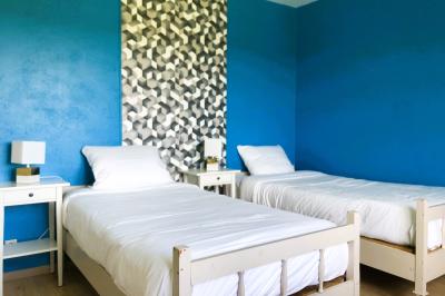 Lit avec tête de lit en métal blanc, draps et oreillers blancs, lampe de chevet sur une table contre un mur vert.