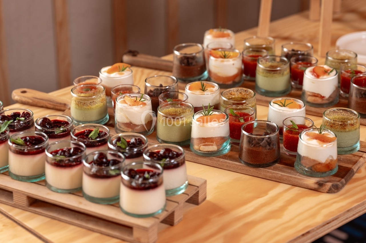 Assortiment de verrines sucrées variées disposées sur des plateaux en bois sur une table.