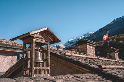 Chalets en bois entourés de neige au pied de montagnes sous un ciel bleu clair.