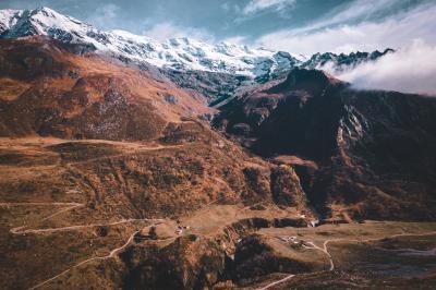Chalets en bois entourés de neige au pied de montagnes sous un ciel bleu clair.
