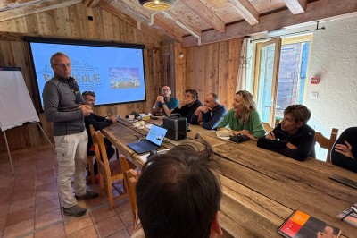 Chalets en bois entourés de neige au pied de montagnes sous un ciel bleu clair.