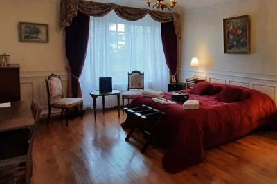 Salon avec canapé et chaises en velours rouge, table basse en bois, lampe sur pied et tableau au mur.
