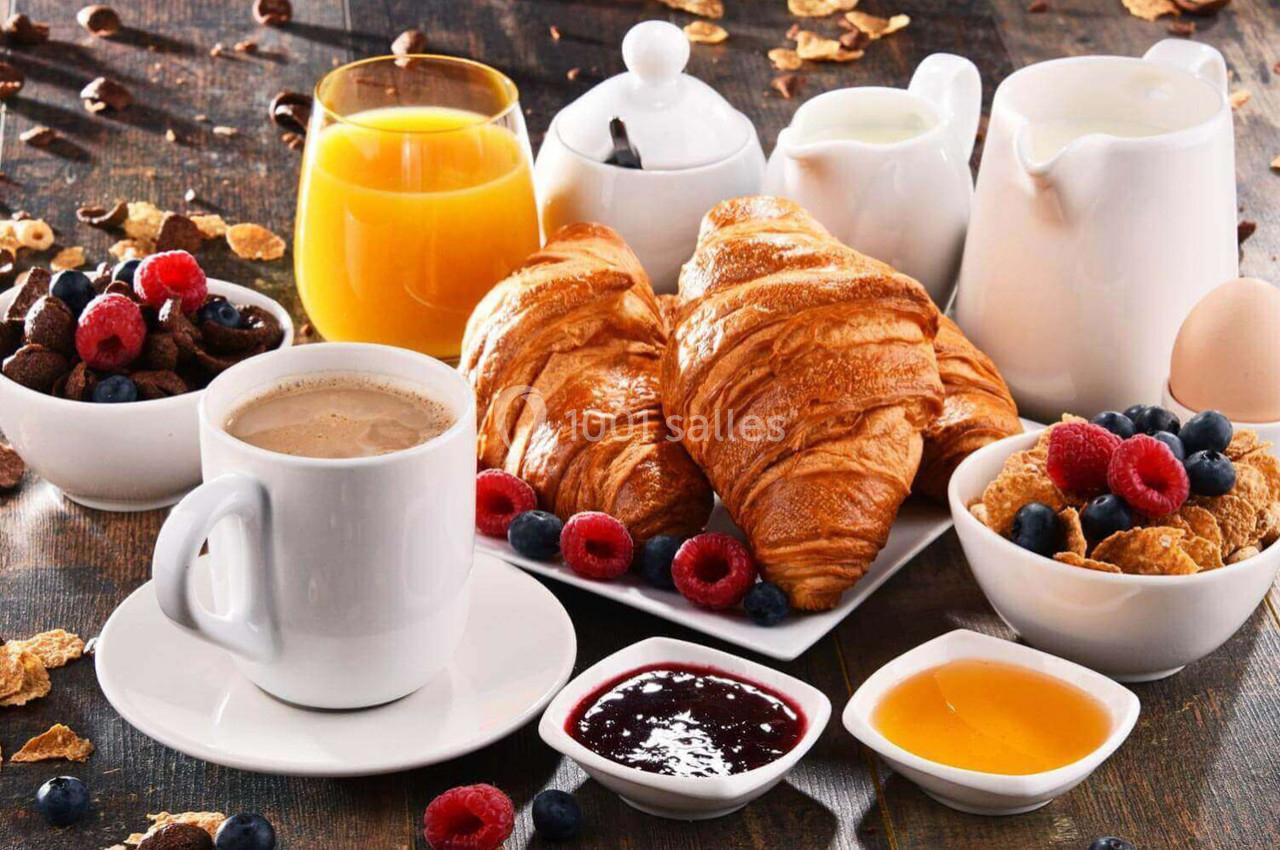 Petit-déjeuner composé de croissants, café, jus d'orange, confitures, céréales, fruits rouges et produits laitiers.
