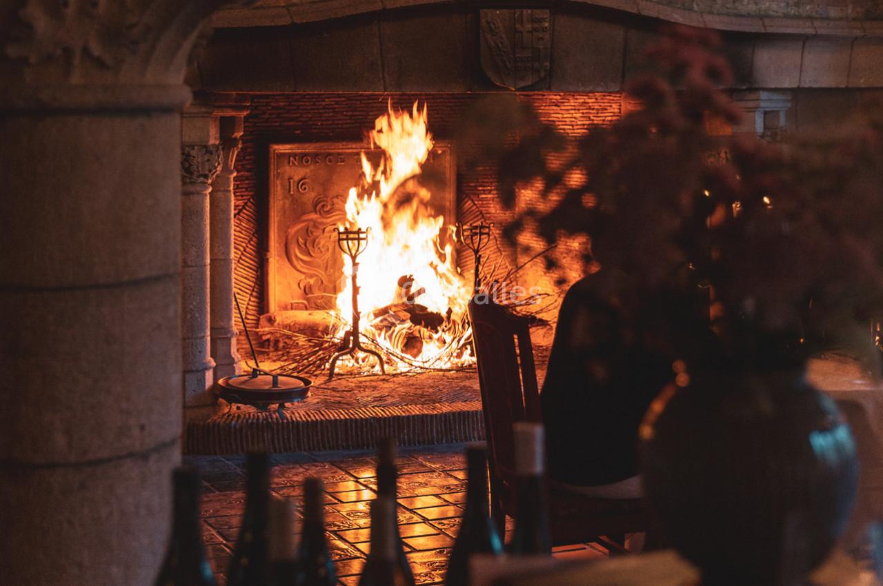 Cheminée en pierre avec un feu de bois allumé, éclairant une pièce chaleureuse avec des objets décoratifs au premier plan.