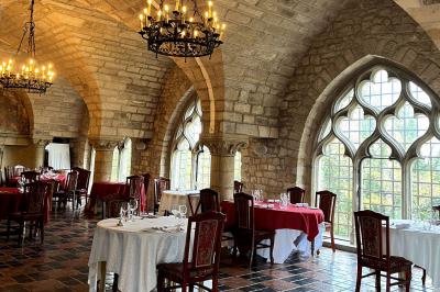 Salon avec canapé et chaises en velours rouge, table basse en bois, lampe sur pied et tableau au mur.