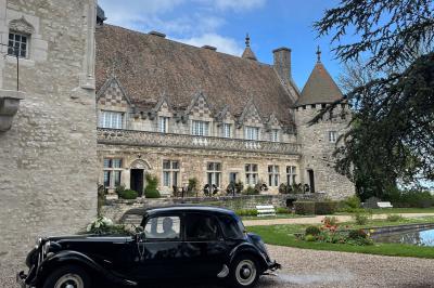 Salon avec canapé et chaises en velours rouge, table basse en bois, lampe sur pied et tableau au mur.