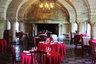 Salon avec canapé et chaises en velours rouge, table basse en bois, lampe sur pied et tableau au mur.