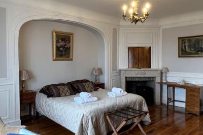 Salon avec canapé et chaises en velours rouge, table basse en bois, lampe sur pied et tableau au mur.