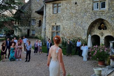 Salon avec canapé et chaises en velours rouge, table basse en bois, lampe sur pied et tableau au mur.