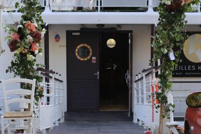 Salle en bois avec de grandes fenêtres, tables en bois décorées pour un repas, chaises pliantes et éclairage suspendu.