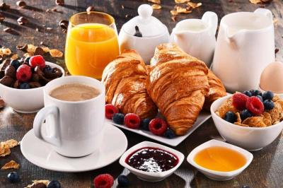 Petit-déjeuner composé de croissants, café, jus d'orange, confitures, céréales, fruits rouges et produits laitiers.