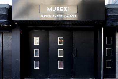 Façade noire d'un établissement nommé ’Murex Paris’ avec des portes vitrées et une enseigne indiquant restaurant, club…