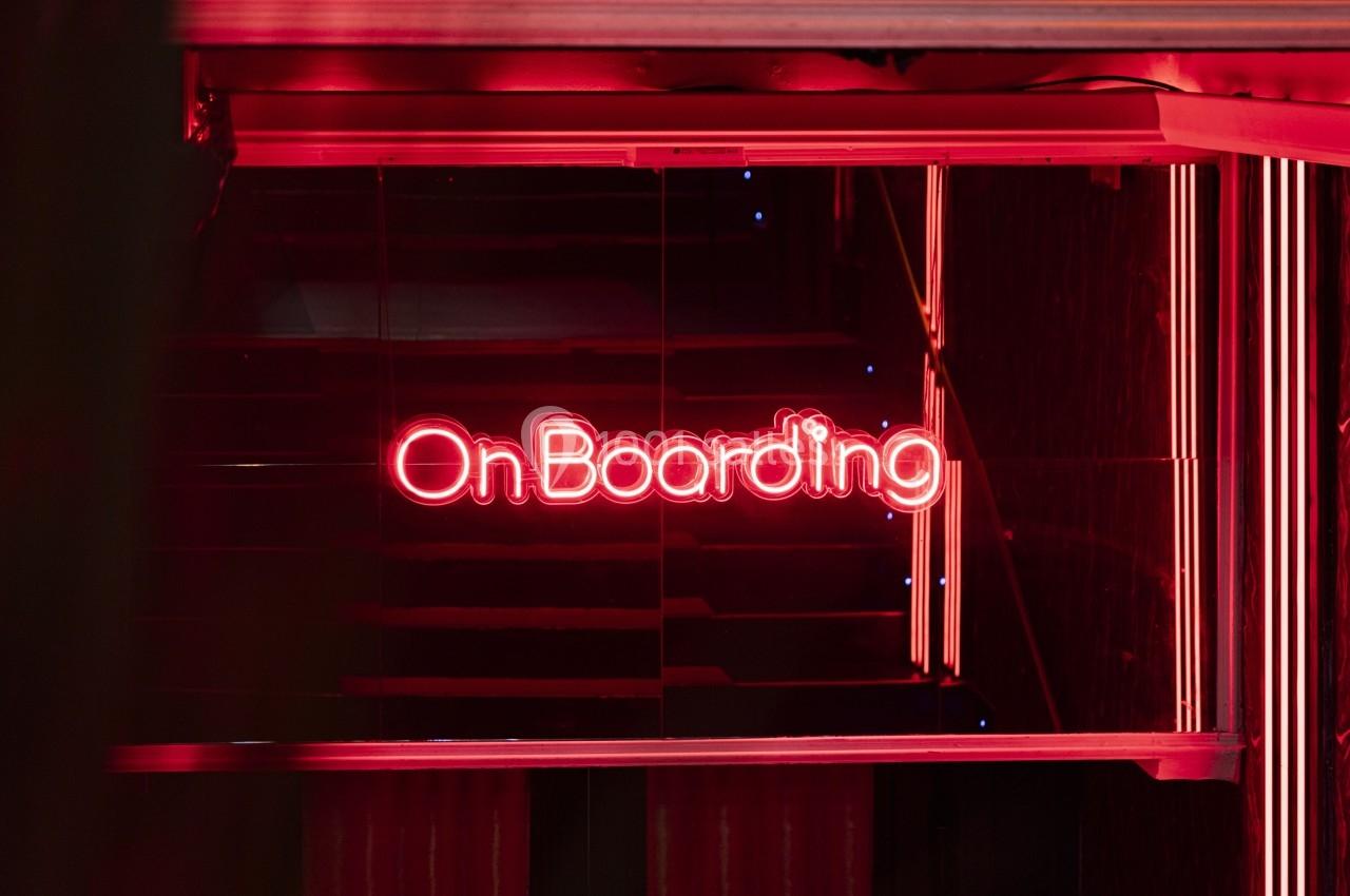 Enseigne lumineuse rouge avec le mot ’OnBoarding’ visible dans un environnement sombre et moderne.
