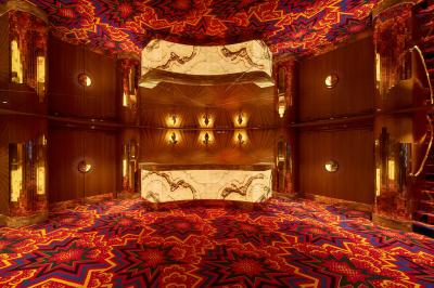 Intérieur d'une pièce aux motifs colorés et symétriques avec des murs en bois, des miroirs et un plafond lumineux.