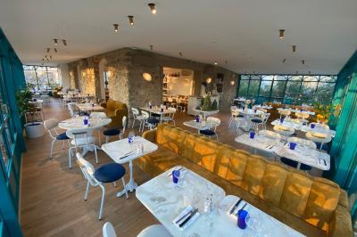 Salle à manger lumineuse avec deux longues tables en marbre blanc, dressées avec des verres bleus et des couverts.
