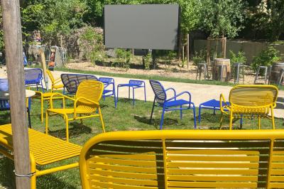 Salle à manger lumineuse avec deux longues tables en marbre blanc, dressées avec des verres bleus et des couverts.