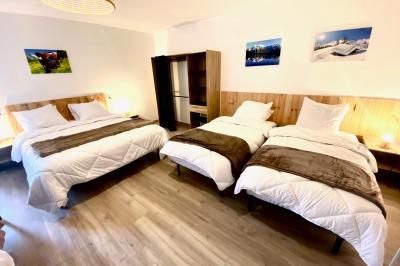 Chambre avec deux lits simples, tablettes de chevet, lampes, parquet et balcon donnant sur un paysage extérieur.