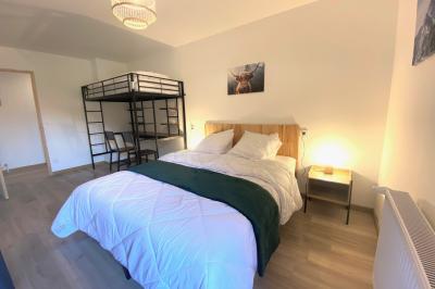 Chambre avec deux lits simples, tablettes de chevet, lampes, parquet et balcon donnant sur un paysage extérieur.