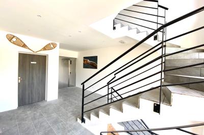 Chambre avec deux lits simples, tablettes de chevet, lampes, parquet et balcon donnant sur un paysage extérieur.