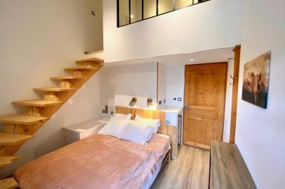 Chambre avec deux lits simples, tablettes de chevet, lampes, parquet et balcon donnant sur un paysage extérieur.