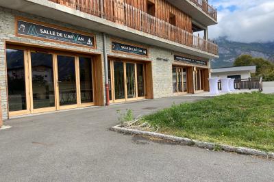 Terrasse spacieuse en carrelage gris avec vue sur des montagnes et des bâtiments en bois sous un ciel dégagé.