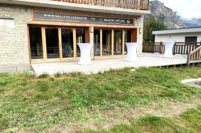 Terrasse spacieuse en carrelage gris avec vue sur des montagnes et des bâtiments en bois sous un ciel dégagé.