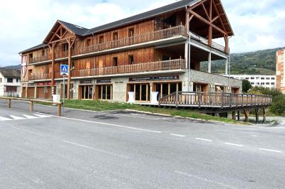 Terrasse spacieuse en carrelage gris avec vue sur des montagnes et des bâtiments en bois sous un ciel dégagé.