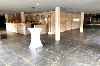 Terrasse spacieuse en carrelage gris avec vue sur des montagnes et des bâtiments en bois sous un ciel dégagé.
