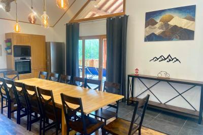 Terrasse spacieuse en carrelage gris avec vue sur des montagnes et des bâtiments en bois sous un ciel dégagé.