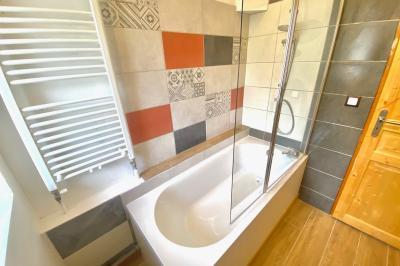 Terrasse spacieuse en carrelage gris avec vue sur des montagnes et des bâtiments en bois sous un ciel dégagé.