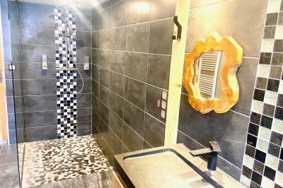 Terrasse spacieuse en carrelage gris avec vue sur des montagnes et des bâtiments en bois sous un ciel dégagé.