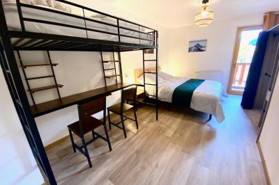 Terrasse spacieuse en carrelage gris avec vue sur des montagnes et des bâtiments en bois sous un ciel dégagé.