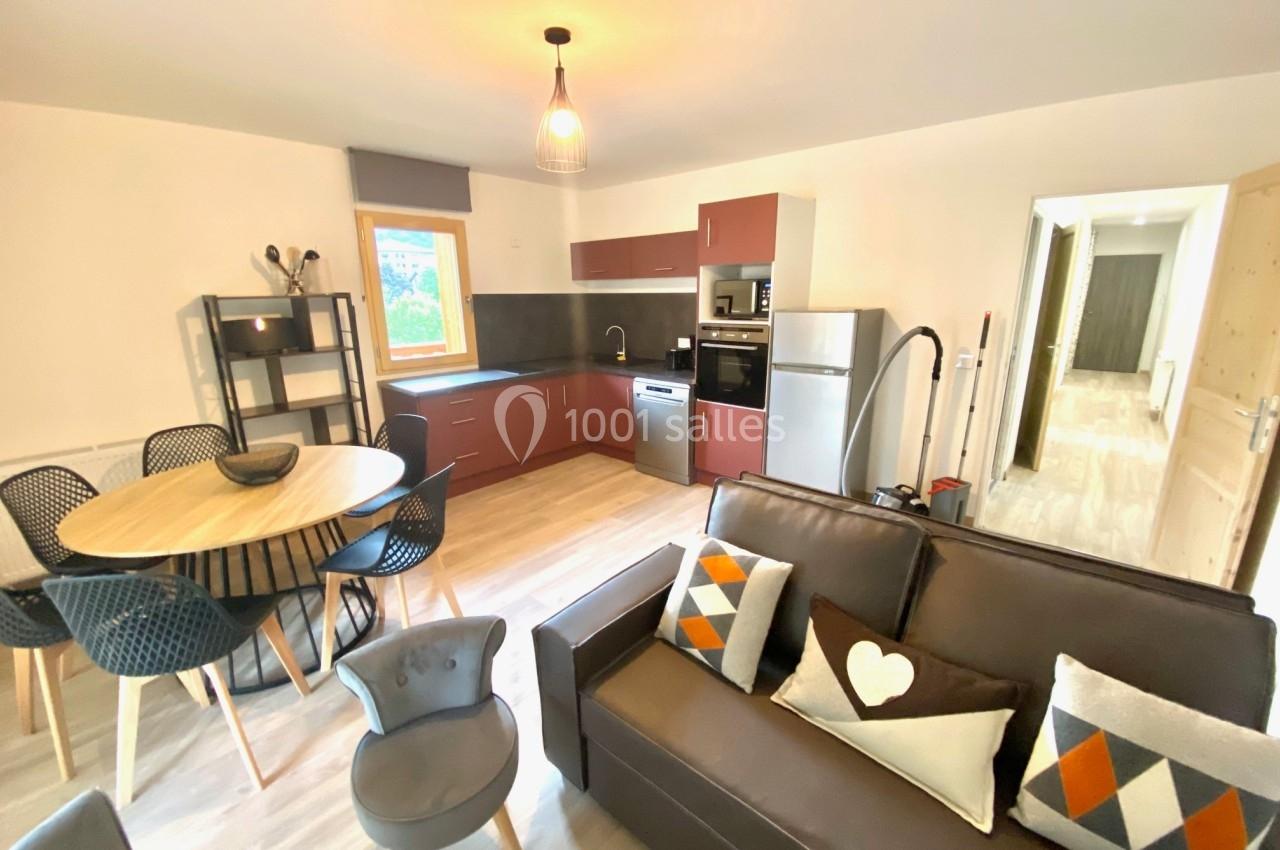 Cuisine ouverte avec table à manger ronde, canapé, et équipements modernes dans un intérieur lumineux.