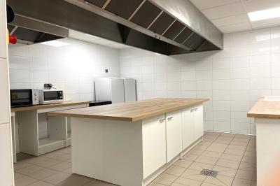 Terrasse spacieuse en carrelage gris avec vue sur des montagnes et des bâtiments en bois sous un ciel dégagé.