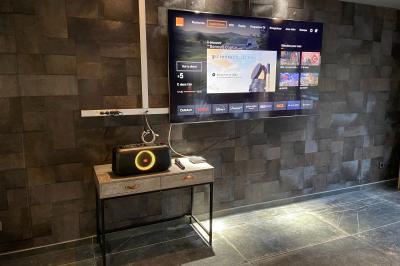 Terrasse spacieuse en carrelage gris avec vue sur des montagnes et des bâtiments en bois sous un ciel dégagé.