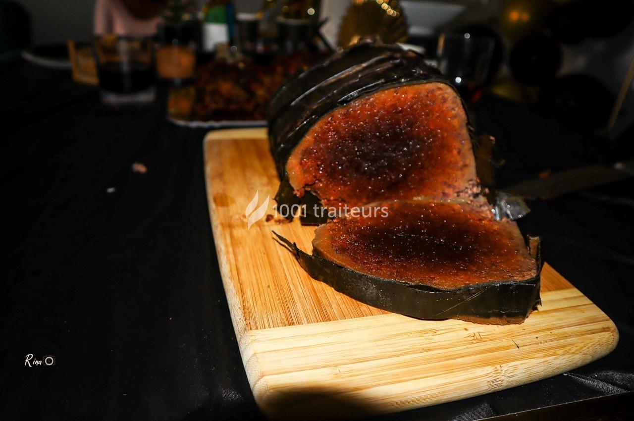 Gâteau enveloppé dans des feuilles, coupé en tranches, posé sur une planche en bois sur une table sombre.