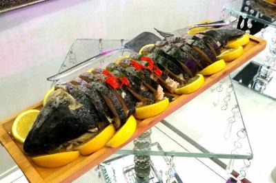 Miniature Traiteur Magny-les-Hameaux (Yvelines) - Iles en Fete #23 Plateau de charcuterie et fromages avec fruits, légumes et une bouteille de vin rouge, présenté sur une table en extérieur.