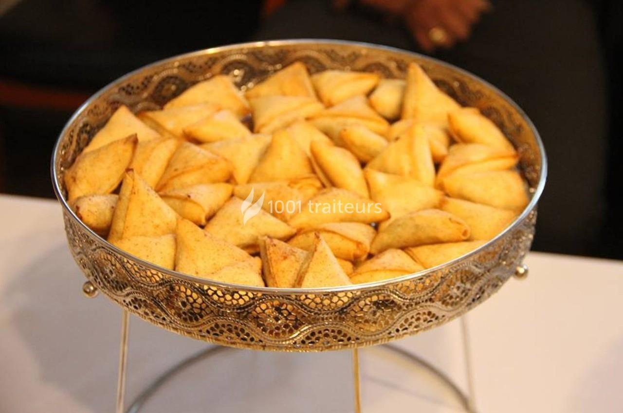 Plateau en métal doré rempli de samoussas dorés et croustillants, posé sur une table blanche.