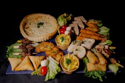 Miniature Traiteur Magny-les-Hameaux (Yvelines) - Iles en Fete #26 Plateau de charcuterie et fromages avec fruits, légumes et une bouteille de vin rouge, présenté sur une table en extérieur.