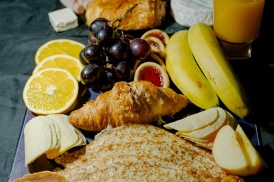 Miniature Traiteur Magny-les-Hameaux (Yvelines) - Iles en Fete #28 Plateau de charcuterie et fromages avec fruits, légumes et une bouteille de vin rouge, présenté sur une table en extérieur.