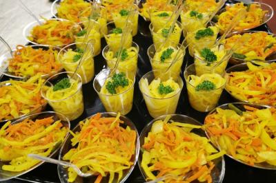 Coupes individuelles de salade de carottes et de légumes jaunes garnies de persil, présentées sur un plateau.