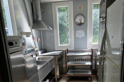 Toilettes avec lavabo, miroir, distributeur de papier, poubelle et carrelage au sol dans un espace restreint.