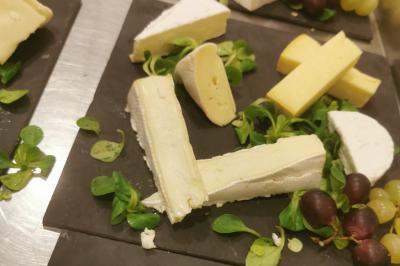 Plateau de charcuterie et fromages avec fruits, légumes, et une bouteille de vin rouge, sur une table en extérieur la nuit.