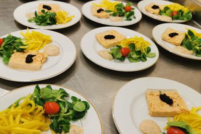 Plateau de charcuterie et fromages avec fruits, légumes, et une bouteille de vin rouge, sur une table en extérieur la nuit.